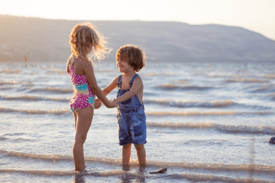 photo of two young girls holding hands on the beach