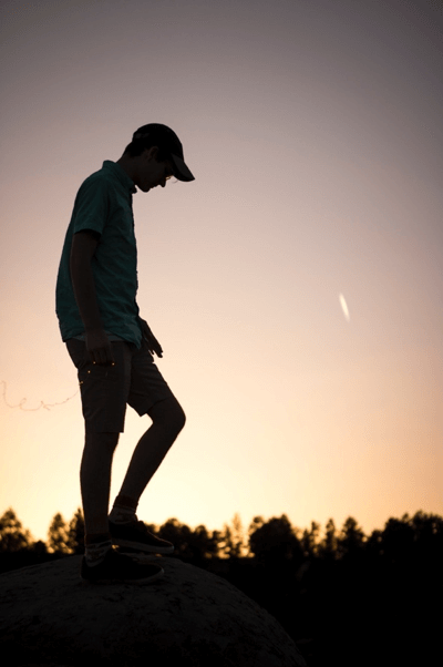 photo of a young man walking alone at sunset 
