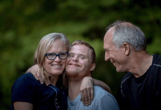 young adult son with Down syndrome hugged by his parents