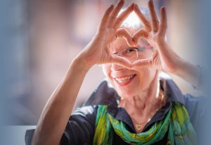 Senior woman smiling and making heart symbol