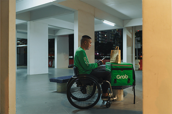 A food delivery employee who uses a wheelchair is checking his orders