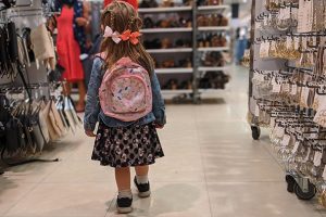 little girl with backpack shopping in a store with dimmed lights for sensory-friendly shopping
