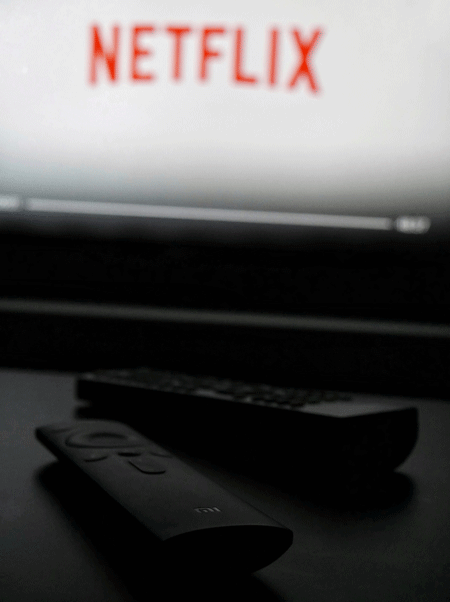 photo of two tv remotes and netflix on the screen in the background